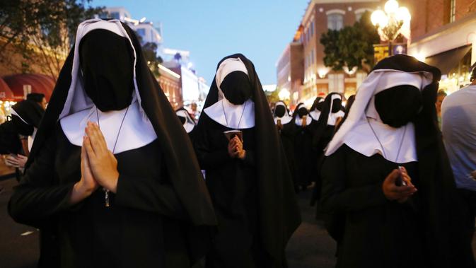 Wanita berpakaian biarawati berjalan sambil mempromosikan film 'The Nun' di luar San Diego Comic-Con, San Diego, California, Amerika Serikat, Kamis (19/7). (Mario Tama/Getty Images/AFP)