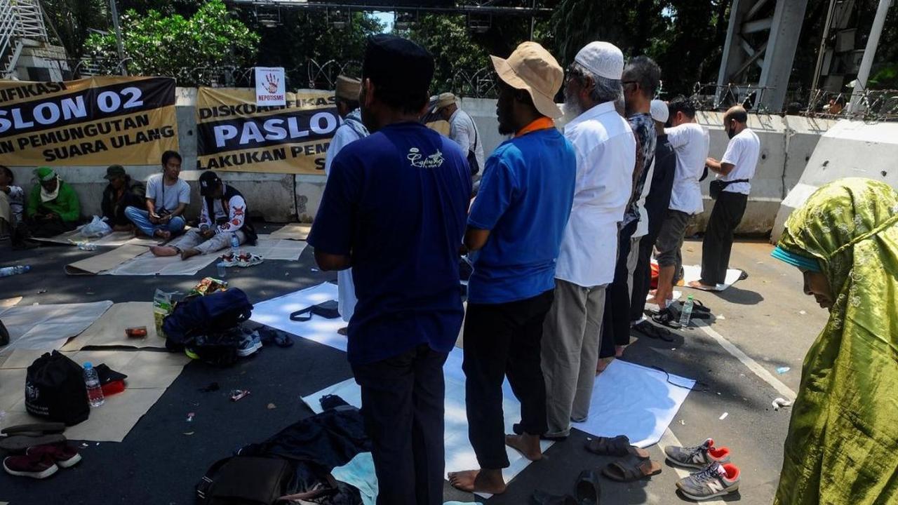 Aksi ini diikuti massa dari Koalisi Nasional Penyelamat Demokrasi (KNPD).<br><br>Mereka mengambil wudhu di air kolam Patung Kuda dan melaksanakan salat dzuhur berjemaah di area Jalan Medan Merdeka Barat. Foto: merdeka.com / Arie Basuki<br>