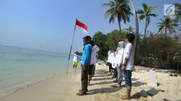 Aktivis Yayasan Kehati Jakarta  dan penjaga pulau melakukan upacara bendera menghadap laut dalam rangka HUT ke-74 RI di Pulau Sangiang, Banten, Minggu (18/8/2019). Kegiatan ini dilakukan serentak secara nasional di 73 titik untuk mencintai laut dan sumber daya alamnya. (merdeka.com/Arie Basuki)