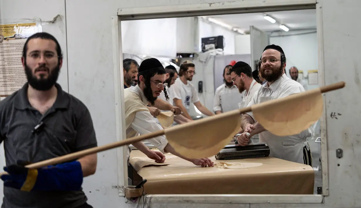 Orang-orang Yahudi ultraortodoks membuat roti matzo di sebuah toko roti di Ashdod, Israel, Selasa (4/4/2023). Matzo adalah roti tanpa ragi yang secara tradisi menjadi simbol keprihatinan bangsa Yahudi. (AP Photo/Tsafrir Abayov)