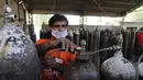 Seorang pekerja mengisi ulang tabung oksigen medis di stasiun pengisian di pinggiran Prayagraj, India, pada 23 April 2021. Pemerintah India berjuang untuk mendapatkan pasokan oksigen ke rumah sakit yang kewalahan oleh ratusan ribu kasus harian baru setiap harinya. (AP Photo/Rajesh Kumar Singh)
