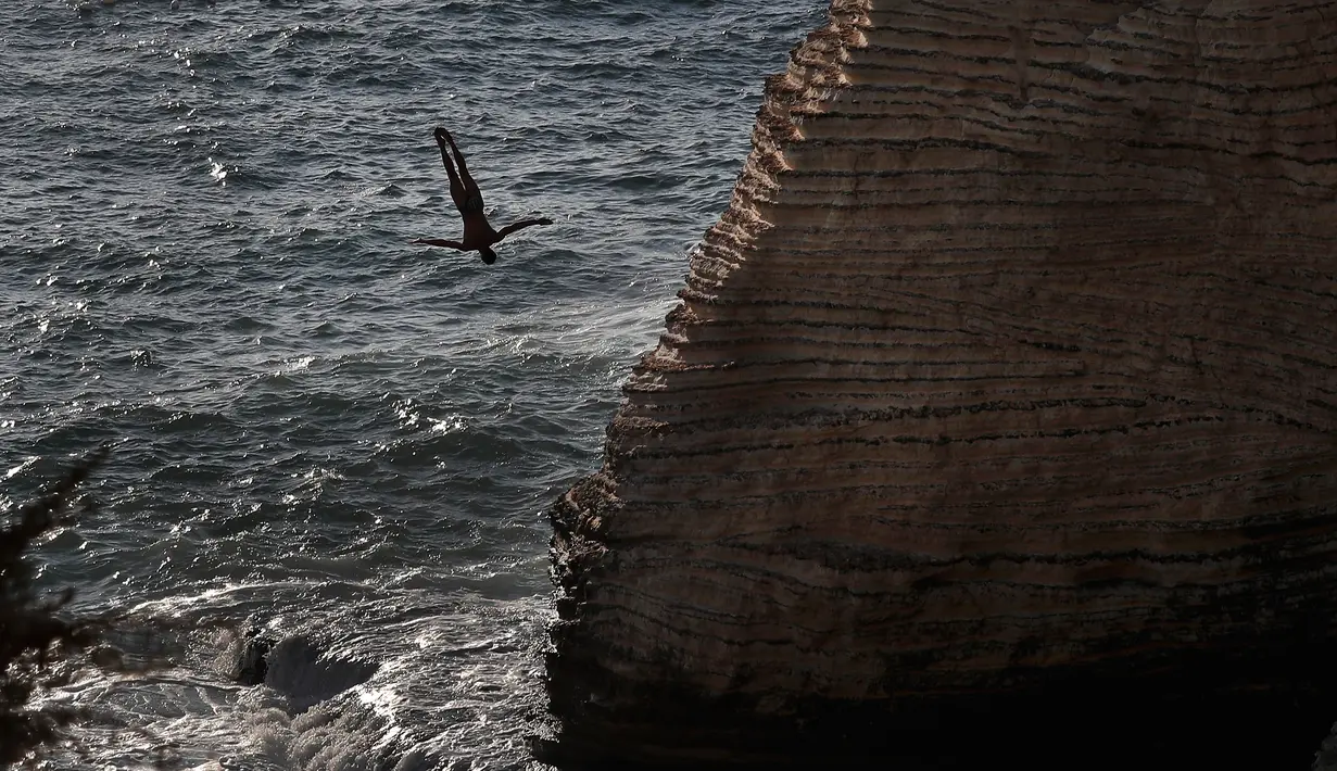 Aksi peserta melompat dari batu karang laut 'Raouche' dalam kompetisi Red Bull Cliff Diving World Series di Beirut, Lebanon, 14 Juli 2019. Sebanyak 40 atlet terdiri dari 10 wanita dan 14 pria yang berasal dari 18 negara melakukan lompatan dari ketinggian 21 - 27 meter. (AP/Hussein Malla)