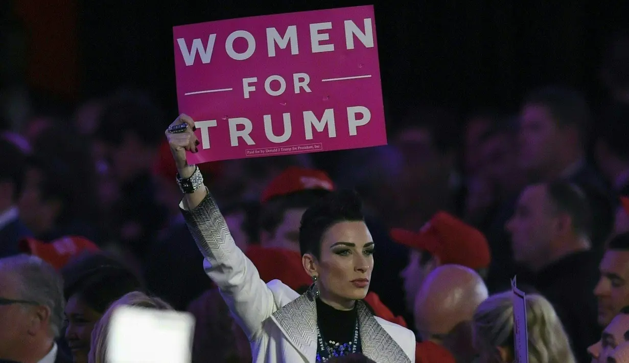 Pendukung mengangkat poster saat menghadiri pidato kemenangan Donald Trump di New York Hilton Midtown di New York, AS, (9/11). Donald Trump mengklaim telah memenangkan electoral votes, unggul dari Hillary Clinton. (AFP PHOTO/Timothy A. Clary)