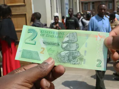 Seorang pria memegang salah satu uang kertas baru yang dikeluarkan Reserve Bank of Zimbabwe di Harare, 12 November 2019. Pemerintah Zimbabwe memperkenalkan kembali mata uang negaranya setelah hampir satu dekade terakhir menggunakan mata uang negara lain untuk bertransaksi. (AP/Tsvangirayi Mukwazhi)