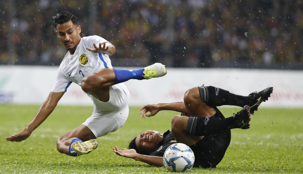 Pemain Malaysia, Muhammad Danial Amier Norhisham (kiri) berebut bola dengan pemain Thailand, Phitiwat Sookjitthummakul pada final sepak bola putra SEA Games 2017 di Stadion Shah Alam, Malaysia (29/8/2017). Thailand menang 1-0. (AP/Vincent Thian)