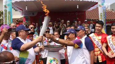 Menteri PPN/Kepala Bappenas Bambang Brodjonegoro (kiri) menyambut Obor Asian Games 2018  dalam Torch Relay atau kirab obor Asian Games di Jakarta Barat di Keluarahan Tanah Sereal, Jakarta Barat, Kamis (16/8).(Liputan6.com/ Herman Zakharia)