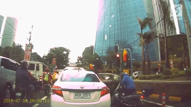 Seorang pengendara motor menabrak pintu mobil taksi yang dibuka mendadak. Insiden ini terjadi di persimpangan jalan kota Taguig, Filipina.