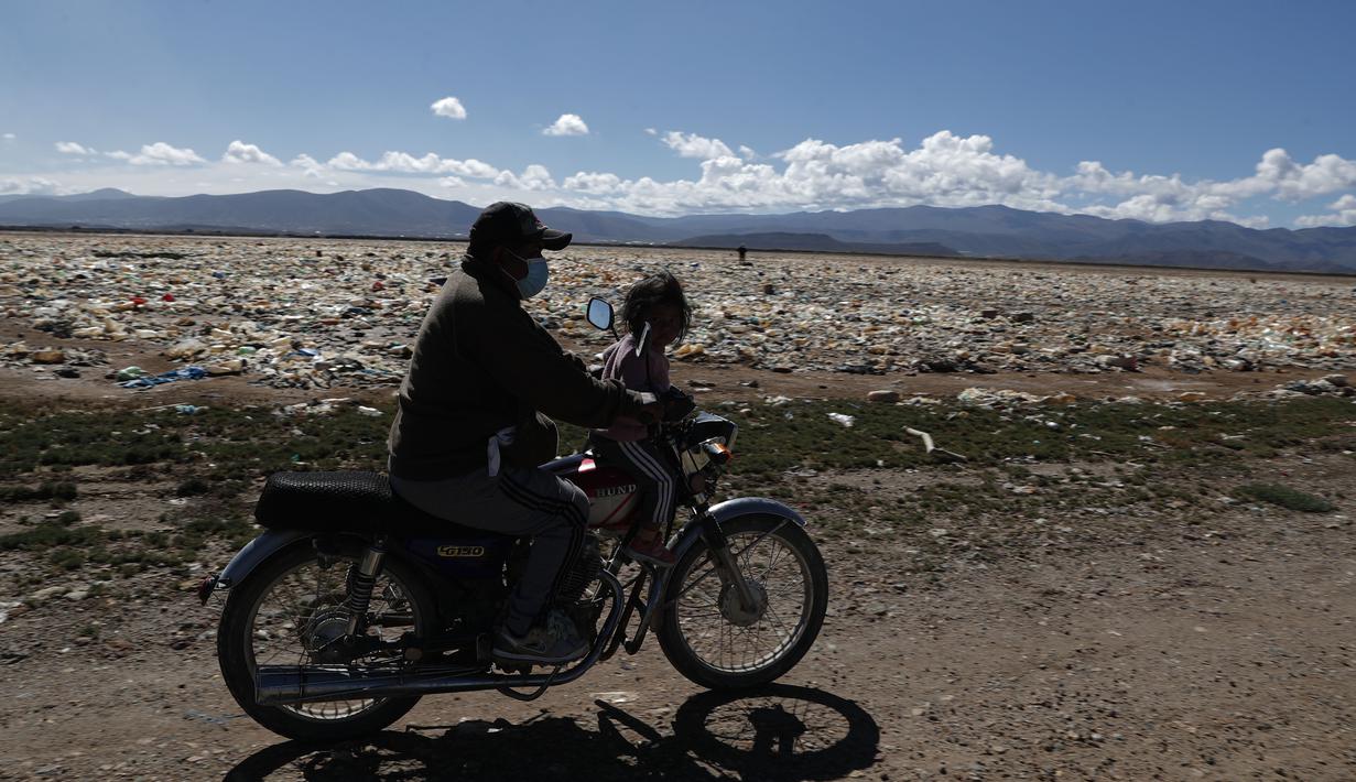 Pengendara sepeda motor melewati sampah di tepian Danau Uru Uru dekat Oruro, Bolivia, Kamis (25/3/2021).  Mayoritas sampah rumah tangga ini terbawa dari aliran sungai yang bermuara di danau ini. (AP Photo / Juan Karita)