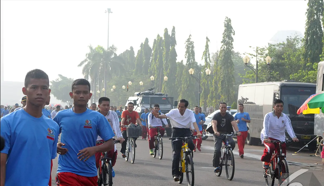 Presiden  Joko Widodo (Jokowi) menyapa warga sambil bersepeda di kawasan Car Free Day, Jakarta, Minggu (23/11/2014) (Liputan6.com/Herman zakharia)