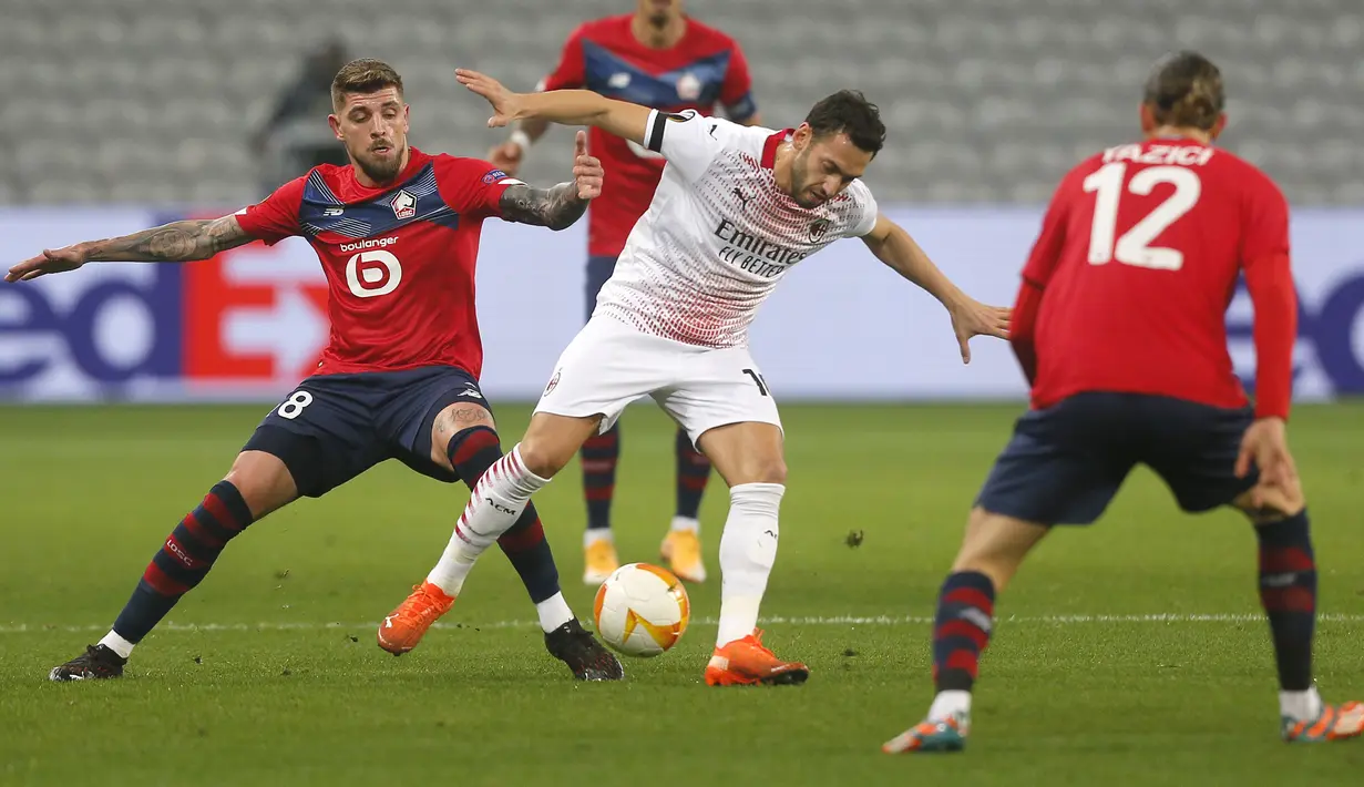 Gelandang AC Milan, Hakan Calhanoglu (kanan) membawa bola dari kawalan pemain Lille, Xeka pada pertandingan lanjutan Grup H Liga Europa di stadion Stade Pierre Mauroy di Villeneuve d'Ascq, Prancis, Kamis (26/11/2020). AC Milan bermain imbang 1-1 atas Lille. (AP Photo/Michel Spingler)