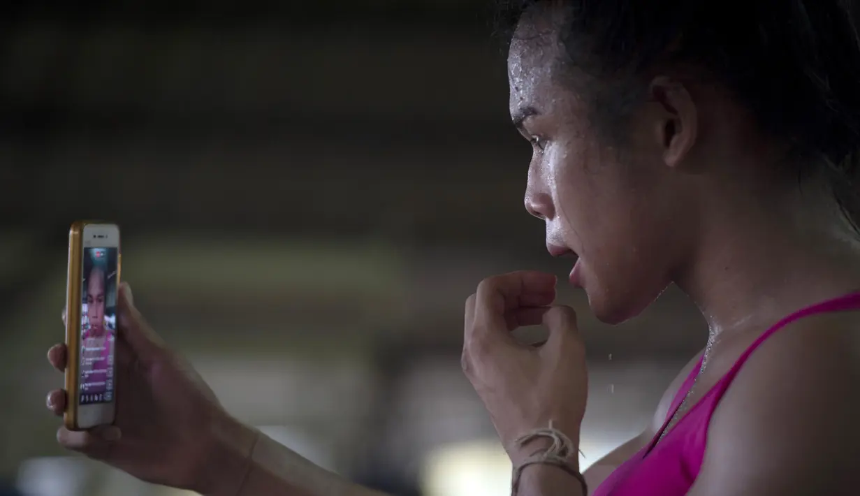 Gaya petinju Muay Thai Nong Rose saat bermain sosial media di sela latihannya di provinsi Chachoengsao, Thailand (15/12). (AFP Photo)