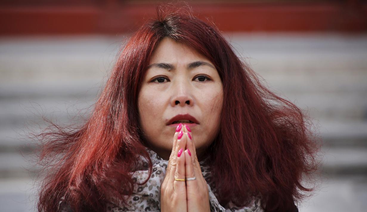 Zheng Liping istri salah satu penumpang pesawat MH370 berdoa untuk suaminya, Ju Kun yang hilang pada tahun 2014 di Kuil Lama di Beijing, Cina,(8/3). Pesawat jet berisi 239 penumpang dan awak ini hilang sejak 8 Maret 2014. (REUTERS/Kim Kyung-hoon)