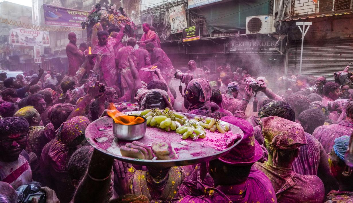 Umat Hindu dengan persembahan berjalan menuju mobil yang membawa patung dewa Krishna selama festival Holi di Kolkata, India, Minggu, 5 Maret 2023. Holi atau Festival Warna adalah festival awal musim semi yang dirayakan di India, Nepal, Bangladesh, dan negara-negara berikut yang memiliki penduduk beragama Hindu. (AP Photo/Bikas Das)