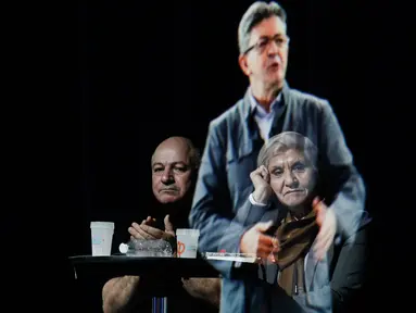 Sepasang tamu duduk sambil mengamati hologram tiga dimensi (3D) calon presiden indepeden Prancis dari kelompok sayap kiri, Jean-Luc Melenchon, yang sedang berpidato di lokasi kampanye di Saint-Denis, dekat Paris, Minggu (5/2). (AP Photo/Kamil Zihnioglu)