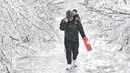 Para pejalan kaki berjalan melewati pepohonan yang tertutup es di Changchun, Provinsi Jilin, China timur laut, pada 19 November 2020. Hujan lebat dan salju yang jarang terjadi disertai angin kencang melanda Changchun pada 18 dan 19 November. (Xinhua/Xu Chang)