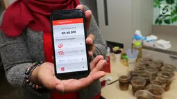 Model menunjukkan total pembayaran pada aplikasi  berbasis mobile yang menawarkan inovasi konsep restoran digital pertama di Indonesia saat Soft Launching Aplikasi MeeberLite dan Meeberian di Jakarta, Selasa (31/7). (Liputan6.com)