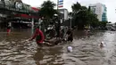 Pengendara sepeda motor menggunakan jasa angkut gerobak saat melintasi banjir di kawasan Green Garden, Jakarta Barat, Selasa (25/2/2020). Hujan yang mengguyur kawasan Jakarta membuat kawasan tersebut tergenang banjir setinggi 60-80 cm. (Liputan6.com/Johan Tallo)