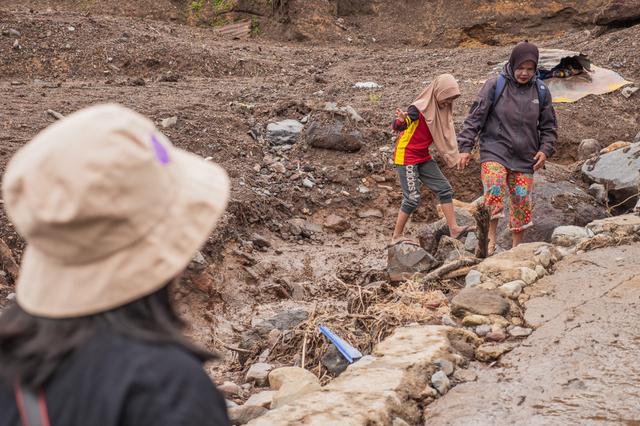Korban banjir melintas di atas tumpukan material sisa banjir Sumbar. (Liputan6.com/Novia Harlina)