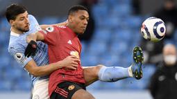 Striker Manchester United, Anthony Martial (kanan) berebut bola dengan bek Manchester City, Ruben Dias dalam laga lanjutan Liga Inggris 2020/21 di Etihad Stadium, Minggu (7/3/2021). MU menang 2-0 atas Mancity. (AFP/Peter Powell/Pool)