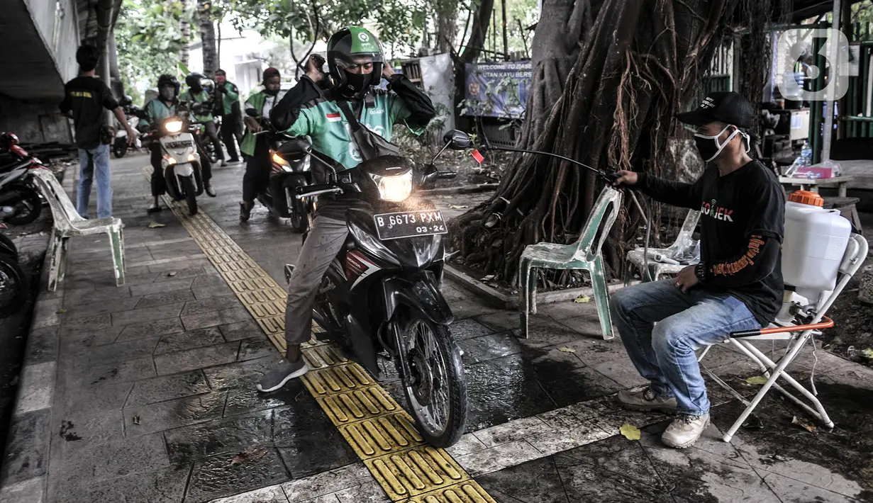 Petugas menyemprotkan cairan disinfektan pada kendaraan pengojek daring saat pemeriksaan rutin di Posko Aman Covid-19, Jakarta, Selasa (11/8/2020). Dalam sehari, Posko Aman Covid-19 rata-rata mampu memeriksa hingga 1.000 pengojek mulai pukul 08.00 WIB-17.00 WIB. (merdeka.com/Iqbal Nugroho)