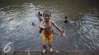 Sejumlah anak mandi di Sungai Ciliwung, Jakarta, Rabu (16/11). Cuaca panas di Jakarta membuat anak-anak tersebut mandi di sungai untuk mendinginkan suhu tubuh. (Liputan6.com/Gempur M Surya)