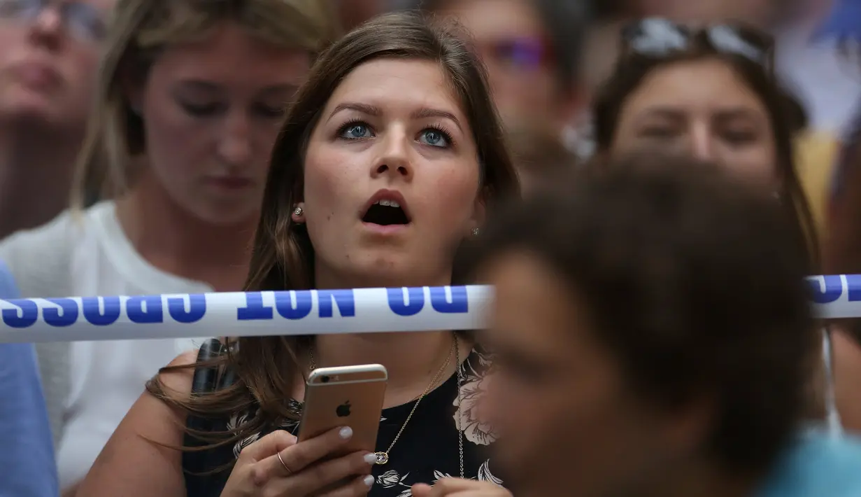 Ekspresi warga ketika menyaksikan seorang pria nekat memanjat gedung Trump Tower di New York, AS, Rabu (10/8). Pria berambut gondrong itu nekat memanjat Menara Trump dengan tali dan cangkir hisap layaknya tengah memanjat tebing. (REUTERS/Carlo Allegri)