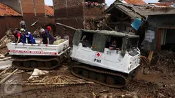 Sukarelawan PMI menaiki kendaran hagglund di Kampung Bojong Sudika, Cimacan, Garut, Jumat (23/9). PMI mengerahkan kendaraan Hagglund untuk membantu proses evakuasi di tengah kawasan yang penuh lumpur akibat banjir bandang. (Liputan6.com/Johan Tallo)