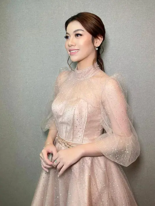 Frislly Herlind tampil anggun berbalut heart neck dress dengan aksen lace dan puff bertabur payet. Untuk hairdo, aktris 22 tahun ini memilih low ponytail. (Instagram/hilgamakeup).
