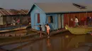 Anak-anak berjalan di atas papan kayu di sebuah desa terapung di sepanjang sungai Siem Reap di Siem Reap, Kamboja (5/12/2019). Sungai Siem Reap adalah sungai yang mengalir melalui Provinsi Siem Reap, di barat laut Kamboja. (AFP/Manan Vatsyayana)