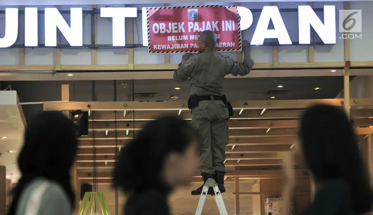 Pengunjung melihat petugas memasang stiker tunggak pajak di salah satu kafe di Green Pramuka Square Mall, Jakarta, Rabu (7/11). Pemilik kios dan kafe di Mall ini sudah tiga kali diberikan peringatan oleh petugas. (Merdeka.com/Iqbal S. Nugroho)