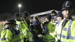 Seorang fans ditahan Polisi setempat setelah berlari memasuki lapangan saat putaran kelima Piala FA antara Arsenal melawan Sutton United di Gander Green Lane stadium, London, (20/2/2017). Arsenal menang 2-0. (AP/Matt Dunham)