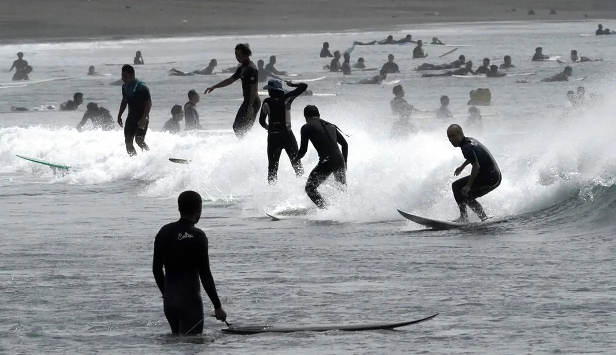 Orang-orang berselancar di pantai Katase-kaigan yang berangin, Fujisawa, Prefektur Kanagawa, selatan Tokyo, Jepang, Kamis (24/9/2020). Badai Tropis Dolphin bergerak di sepanjang pantai Pasifik Jepang. (AP Photo/Eugene Hoshiko)