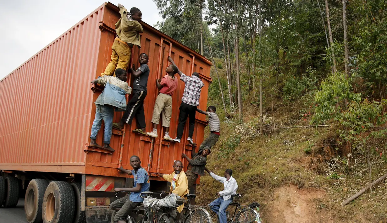 Para pengendara sepeda menggelantung di belakang sebuah truk di luar ibukota Bujumbura, Burundi, (19/7/ 2015). Negara ini akan menggelar pemilihan presiden pekan depan. (REUTERS/Mike Hutchings)