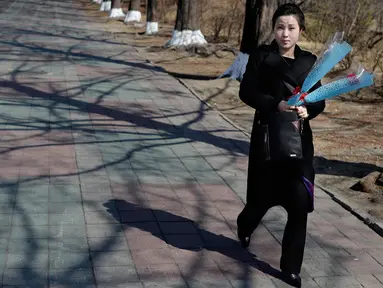 Seorang wanita membawa bunga saat menandai Hari Perempuan Internasional di Pyongyang, Korea Utara, Jumat (8/3). Hari Perempuan Internasional jatuh pada tanggal 8 Maret setiap tahunnya. (AP Photo/Dita Alangkara)
