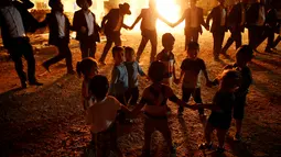Anak-anak menari di samping api unggun selama perayaan hari libur Yahudi Lag Ba-Omer di Shearim, Yerusalem, (25/5). Lag Ba-Omer merupakan hari libur Yahudi yang dirayakan pada hari ke-33 dari Penghitungan Omer. (REUTERS/Ronen Zvulun)