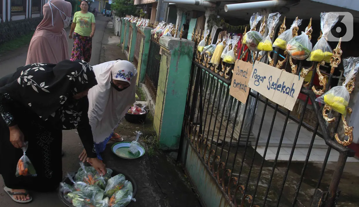 Warga menggantungkan sayuran, beras, dan bumbu masak untuk digantungkan pada pagar rumah di Gang Palautan, Cilodong, Depok, Jumat (21/1/2022). Warga Rt 04 Rw 01 di kawasan tersebut secara swadaya berbagi setiap hari Jumat kepada warga lainnya yang terdampak pandemi. (Liputan6.com/Herman Zakharia)