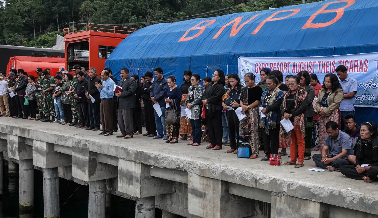 Keluarga dan warga berdoa untuk penumpang yang hilang dari kecelakaan KM Sinar Bangun di Danau Toba di Pelabuhan Tigaras, Sumatra Utara, Indonesia (21/6). KM Sinar Bangun tenggelam pada Senin (18/6) sore. (AFP Photo/Ivan Damanik)