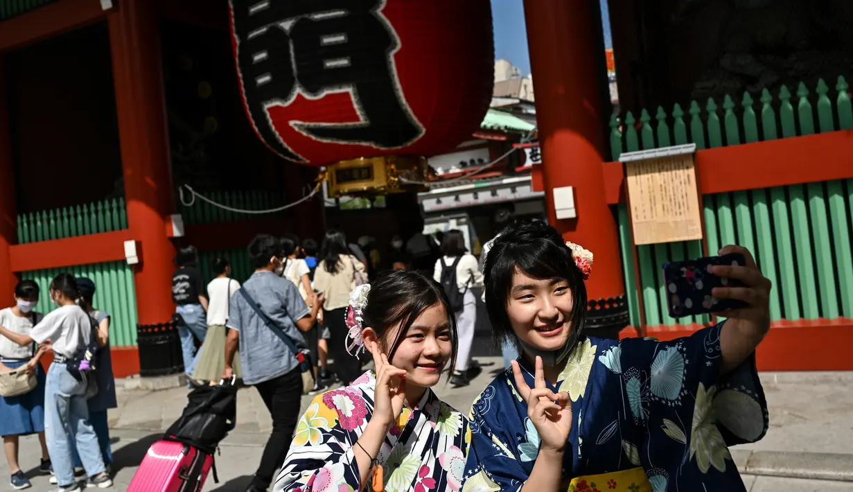Dua wanita mengenakan kimono berpose di pintu masuk kuil Sensoji di distrik Asakusa Tokyo (22/9/2020). Kuil tersebut masih berdiri kokoh dan menjadi salah satu destinasi wajib para wisatawan yang datang ke Tokyo. (AFP/Charly Triballeau)