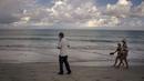 Petugas keamanan memeriksa pantai saat turis berjalan di pantai hotel Iberostar Selection Varadero di Varadero, Kuba, Rabu (29/9/2021). Pihak berwenang di Kuba mulai melonggarkan pembatasan COVID-19 di beberapa kota seperti Havana dan Varadero. (AP Photo/Ramon Espinosa)