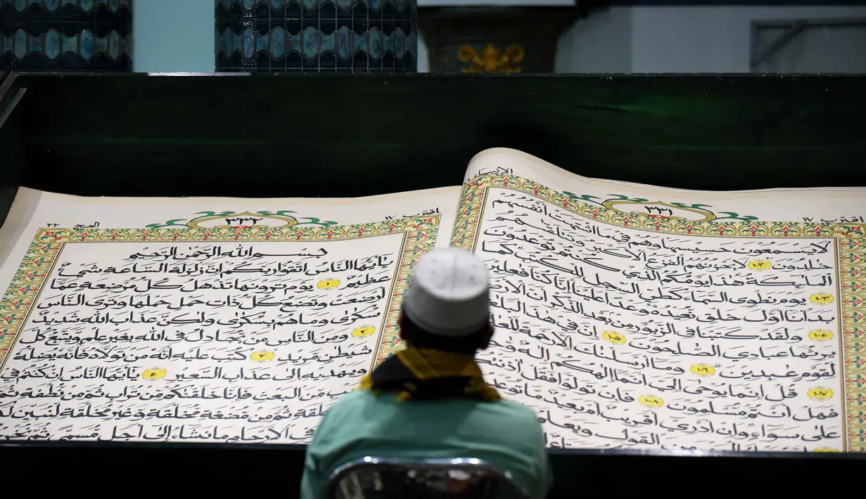 Umat Islam membaca Al-Quran raksasa yang ditulis tangan, berukuran 142 x 210 cm, selama bulan suci Ramadan, di Masjid Baiturrahman, Banyuwangi, Jawa Timur, pada 26 Maret 2024. (Noly Falah/AFP)