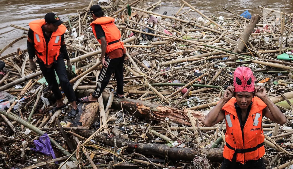 Petugas kebersihan saat mengenakan topeng Spiderman membersihkan sampah yang menumpuk di Pintu Air Manggarai, Jakarta, Senin (12/11). Sampah kiriman berasal dari wilayah Bogor dan Depok. (Liputan6.com/Fery Pradolo)