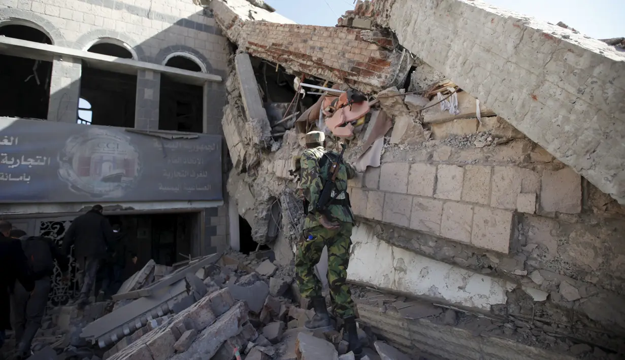 Militan Houthi melihat reruntuhan bangunan Perdagangan dan Industri yang hancur di Sanaa, Yaman, (5/1). Koalisi yang dipimpin Arab Saudi intensifkan serangan udara ke Yaman, Targetnya milisi Syiah Houthi yang didukung Iran. (REUTERS / Khaled Abdullah)
