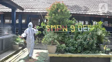 Petugas sekolah menyemprotkan disinfektan usai Pembelajaran Tatap Muka (PTM) 100 persen di SMP Negeri 9 Depok, Cipayung, Jawa Barat, Senin (24/1/2022). Pihak sekolah melakukan penyemprotan disinfektan secara rutin seiring dimulainya pelaksanaan PTM 100 persen di Depok. (merdeka.com/Iqbal S Nugroho)