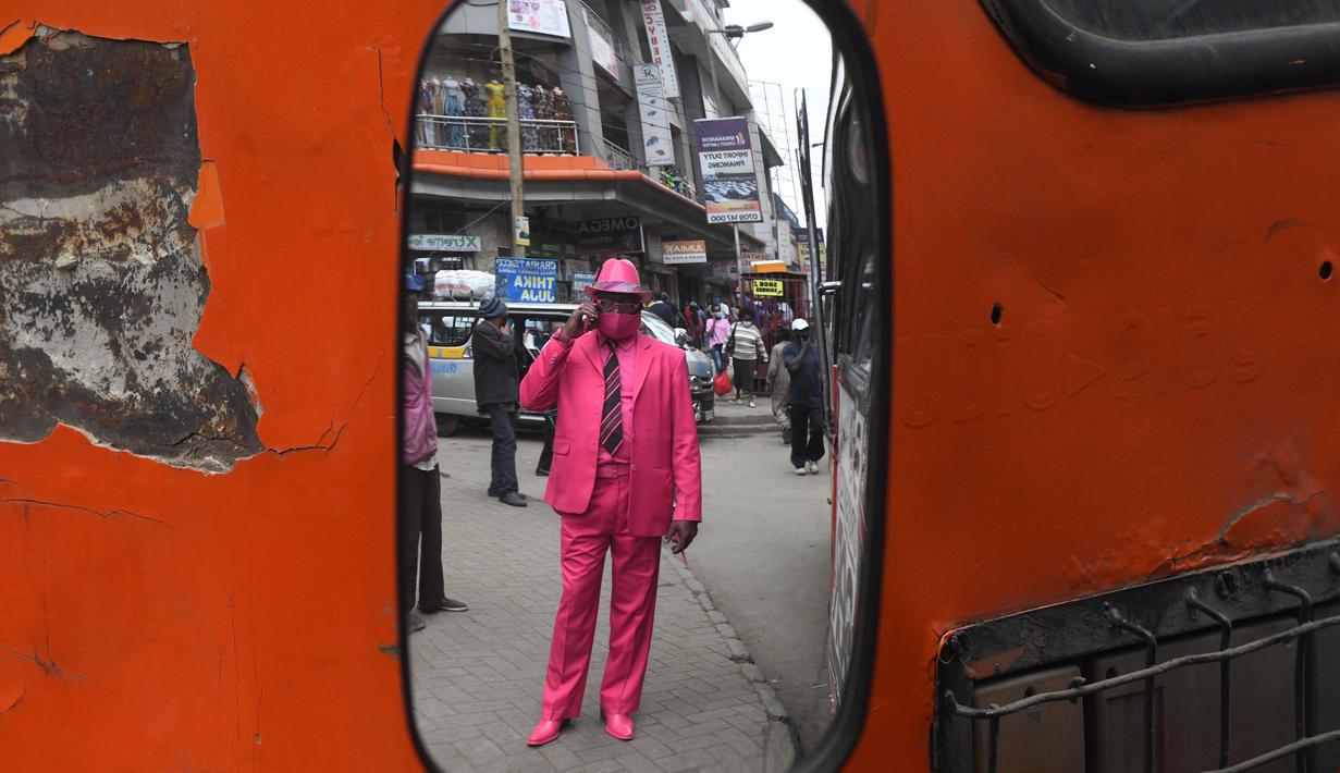 Fashionista Kenya, James Mwangi Maina bermain ponsel sambil memamerkan setelan jasnya yang senada dengan pakaian dan aksesorisnya, termasuk masker di Nairobi, 5 Agustus 2020. Mwangi mengklaim dirinya memiliki penampilan terbaik dan paling stylish di Afrika. (Simon MAINA/AFP)