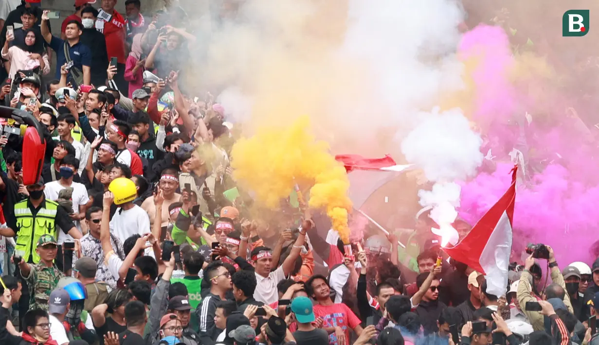 Sejumlah masyarakat menyalakan bom asap  saat menyambut Timnas Indonesia U-22 dan kontingen Indonesia untuk SEA Games 2023 saat pawai Kira87uara yang berlangsung dari Kemenpora hingga GBK, Jakarta, Jumat (19/05/2023). (Bola.com/M Iqbal Ichsan)
