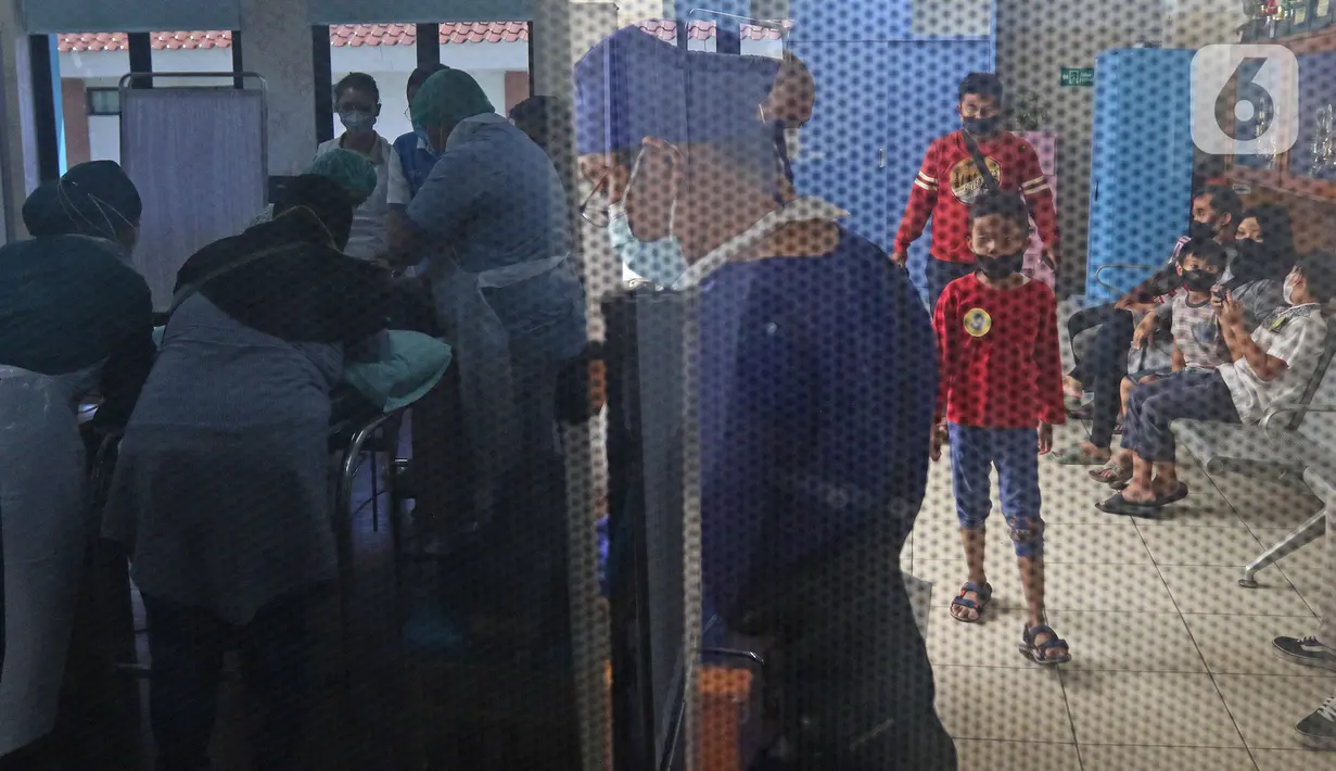 Suasana sunat massal terefleksi dari kaca jendela di Puskesmas Kecamatan Cilandak, Jakarta, Kamis (2/12/2021). Kegiatan sunat massal secara gratis tersebut digelar di 10 Puskesmas di wilayah Jakarta Selatan. (Liputan6.com/Herman Zakharia)