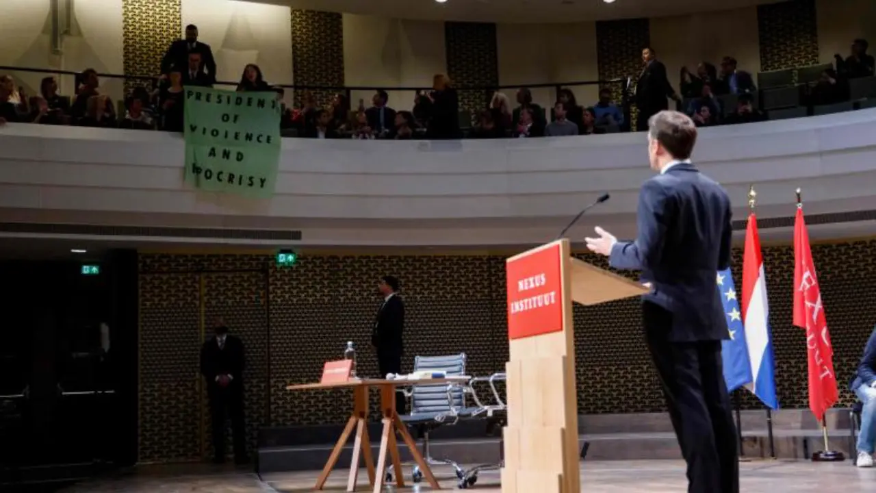 Presiden Prancis Emmanuel Macron menatap spanduk yang menyebutnya munafik.