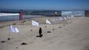 Seorang pria melintas di dekat seni instalasi kontemporer "Tu huella es el camino, tu bandera es de paz" di Playas de Tijuana, Meksiko (7/10). (AFP Photo/Guillermo Arias)