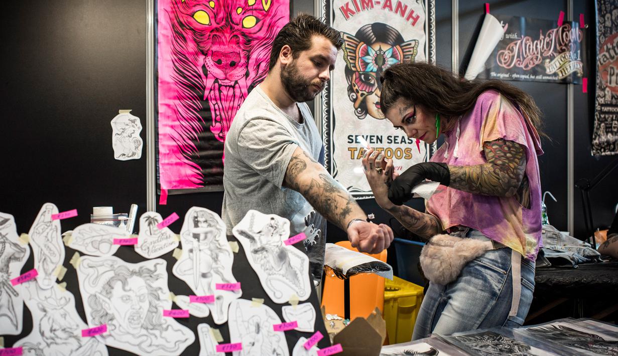 Seorang seniman tato serius menggambar di tangan pria selama acara Paris Tattoo Convention di Grand Halle de la Villette, Paris, Prancis, Jumat (9/3). Paris Tattoo Convention tahun ini merupakan yang kedelapan. (Philippe LOPEZ/AFP)