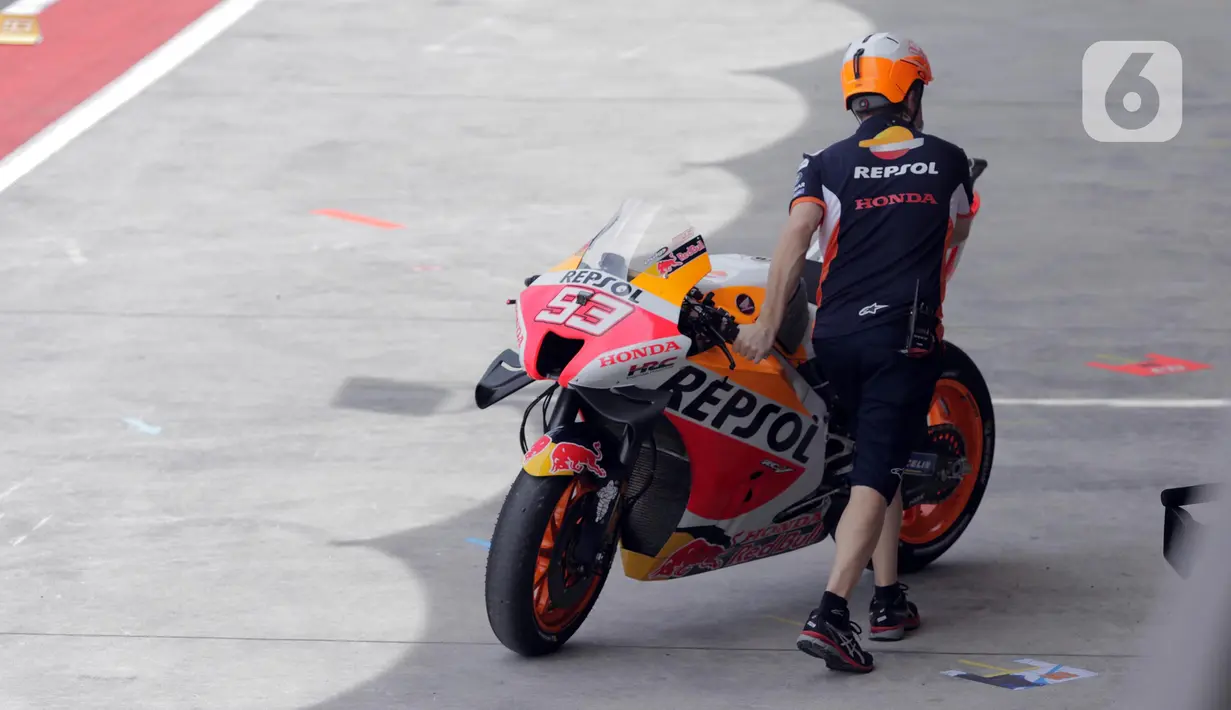 Teknisi Repsol Honda Team mendorong motor tunggangan Marc Marquez saat sesi Warm Up MotoGP di Pertamina Mandalika International Street Sirkuit, Nusa Tenggara Barat, Minggu (20/3/2022). (Liputan6.com/Helmi Fithriansyah)